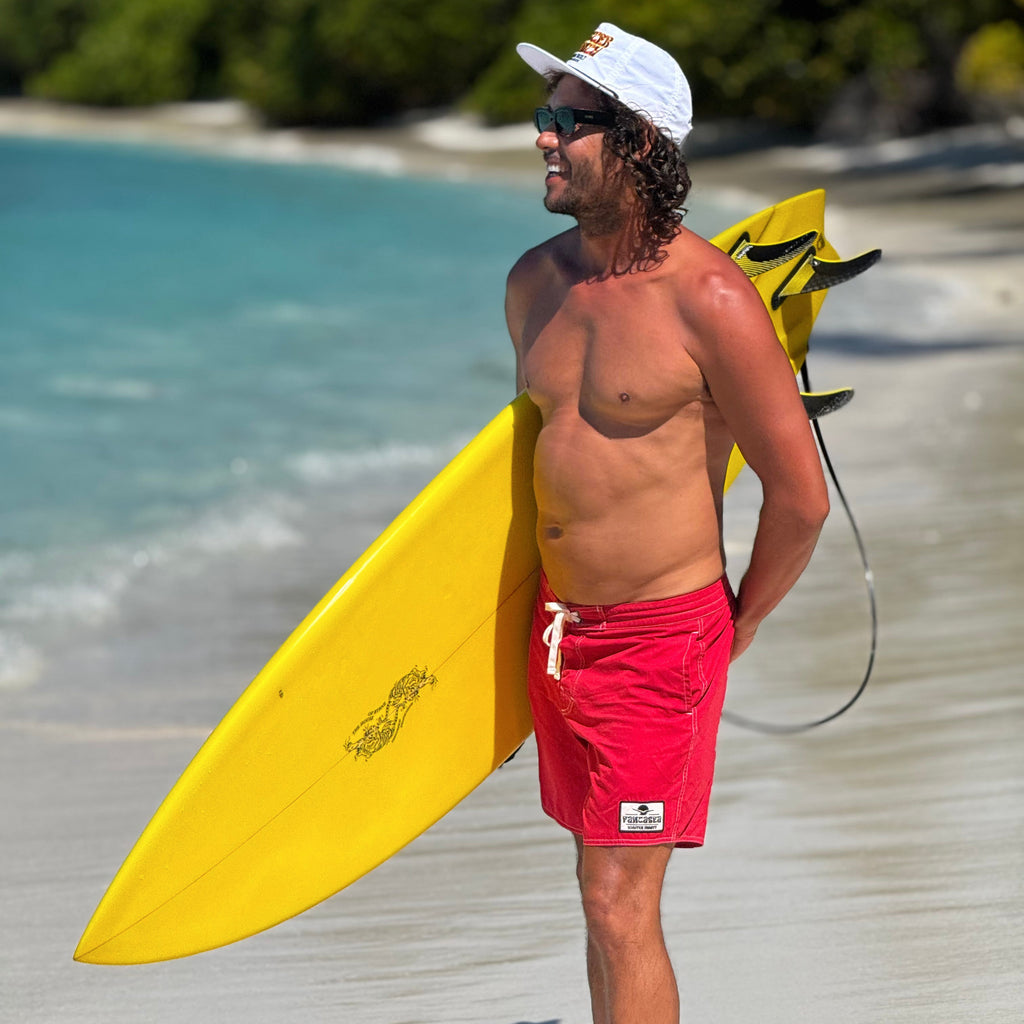 Man holding a yellow surfboard on a beach