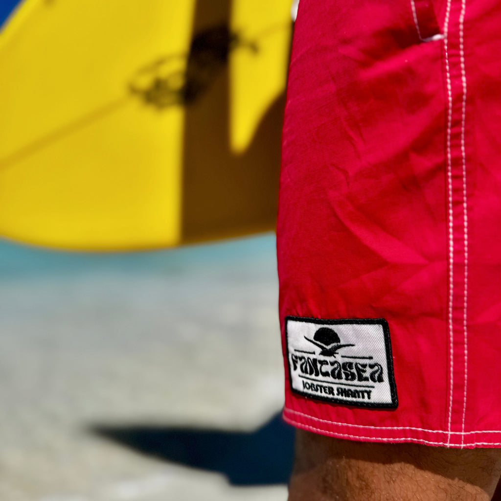 Red swim shorts with a visible brand logo on a beach.